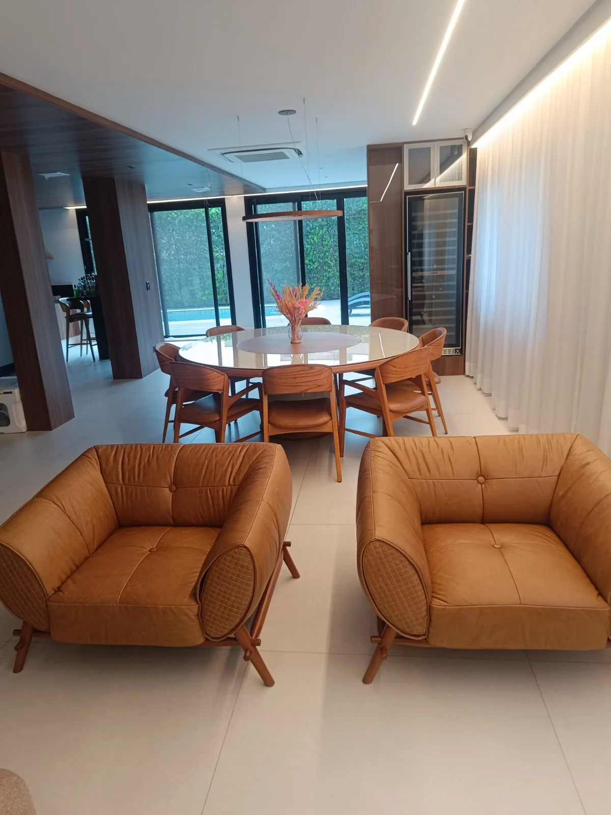 Poltronas de couro caramelo integradas à sala de jantar