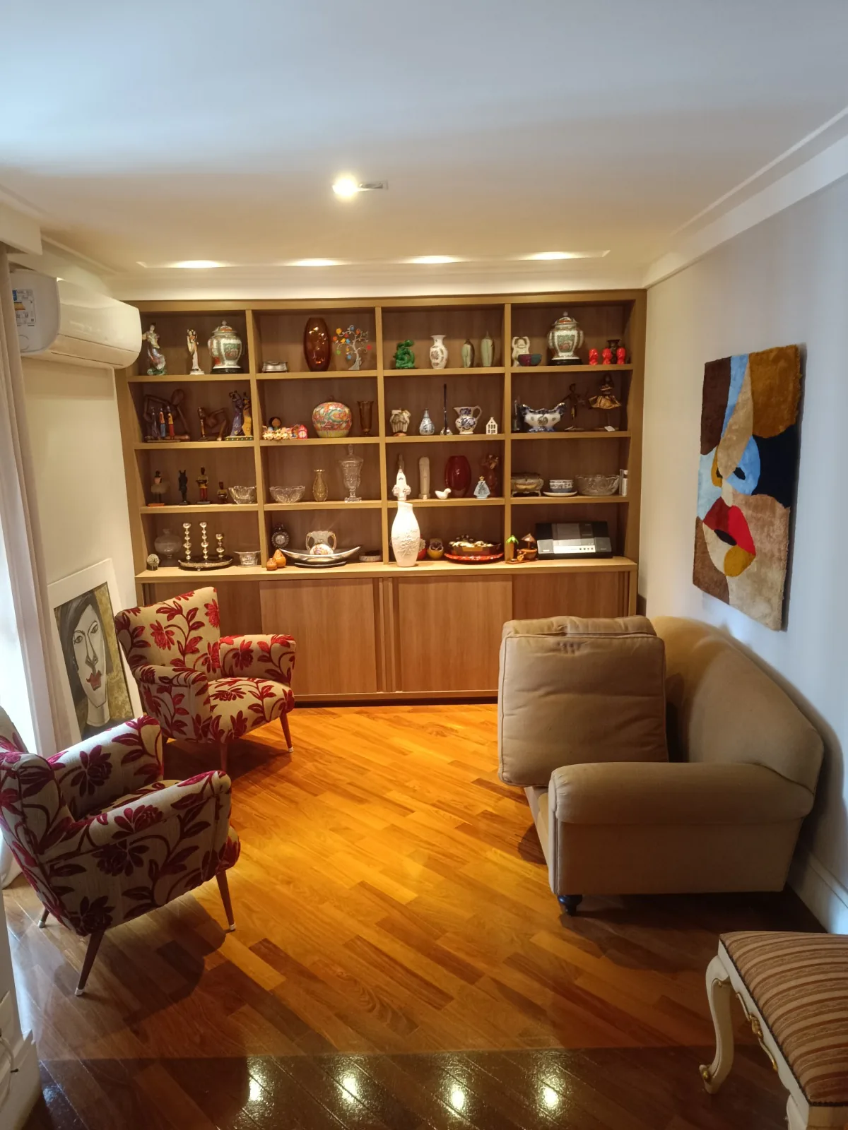 Sala com estante de madeira e poltronas floridas