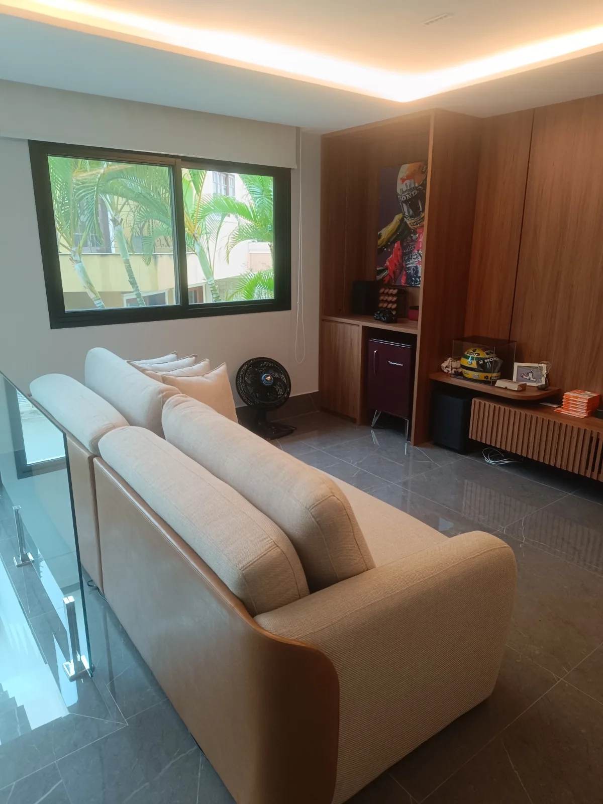 Sofá bege curvo com painel de madeira