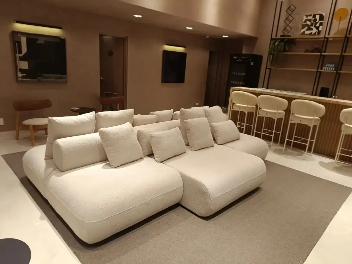 Sala ampla com sofá branco em L e bancada de jantar