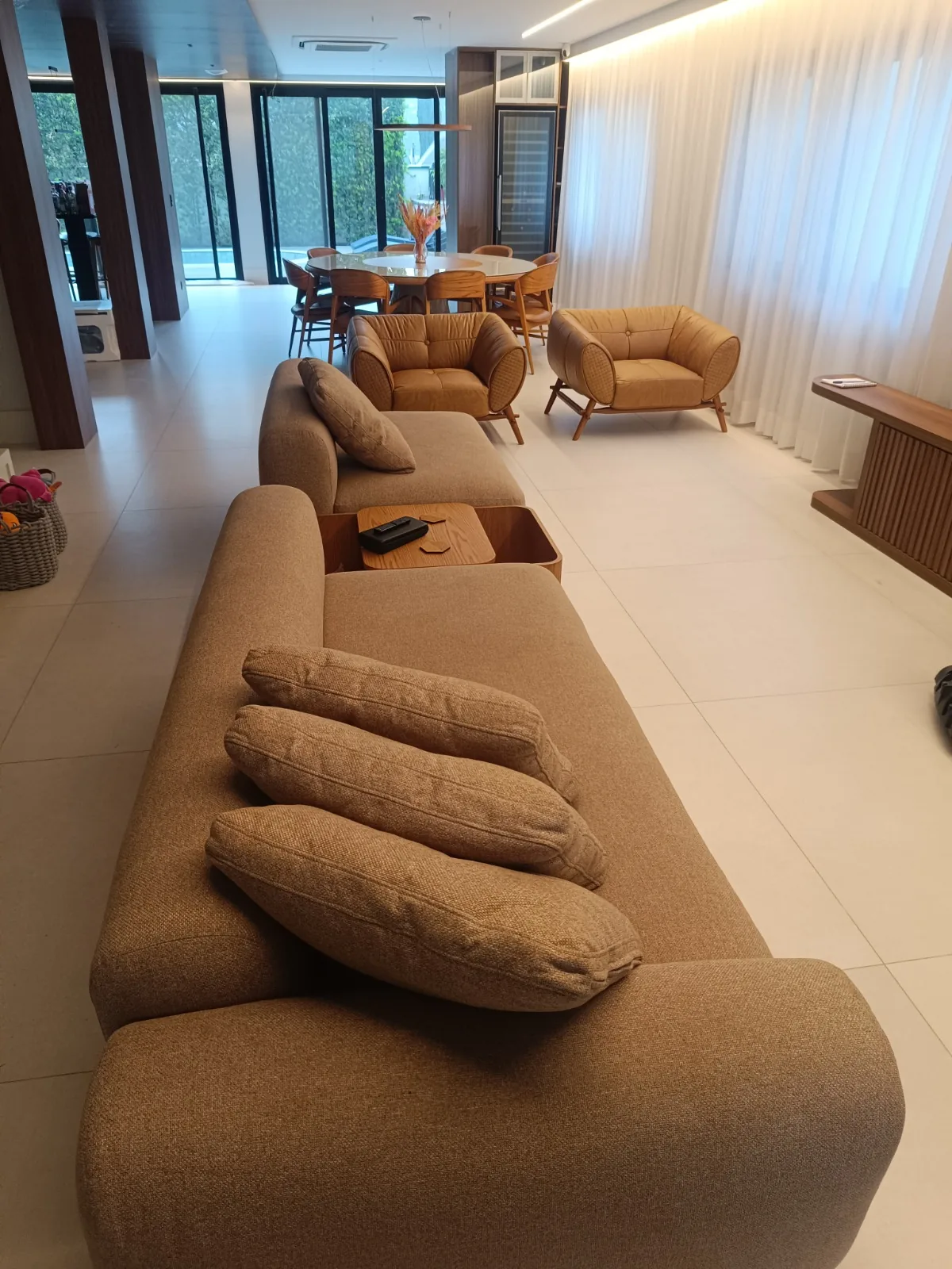 Sofá caramelo em sala ampla de piso claro