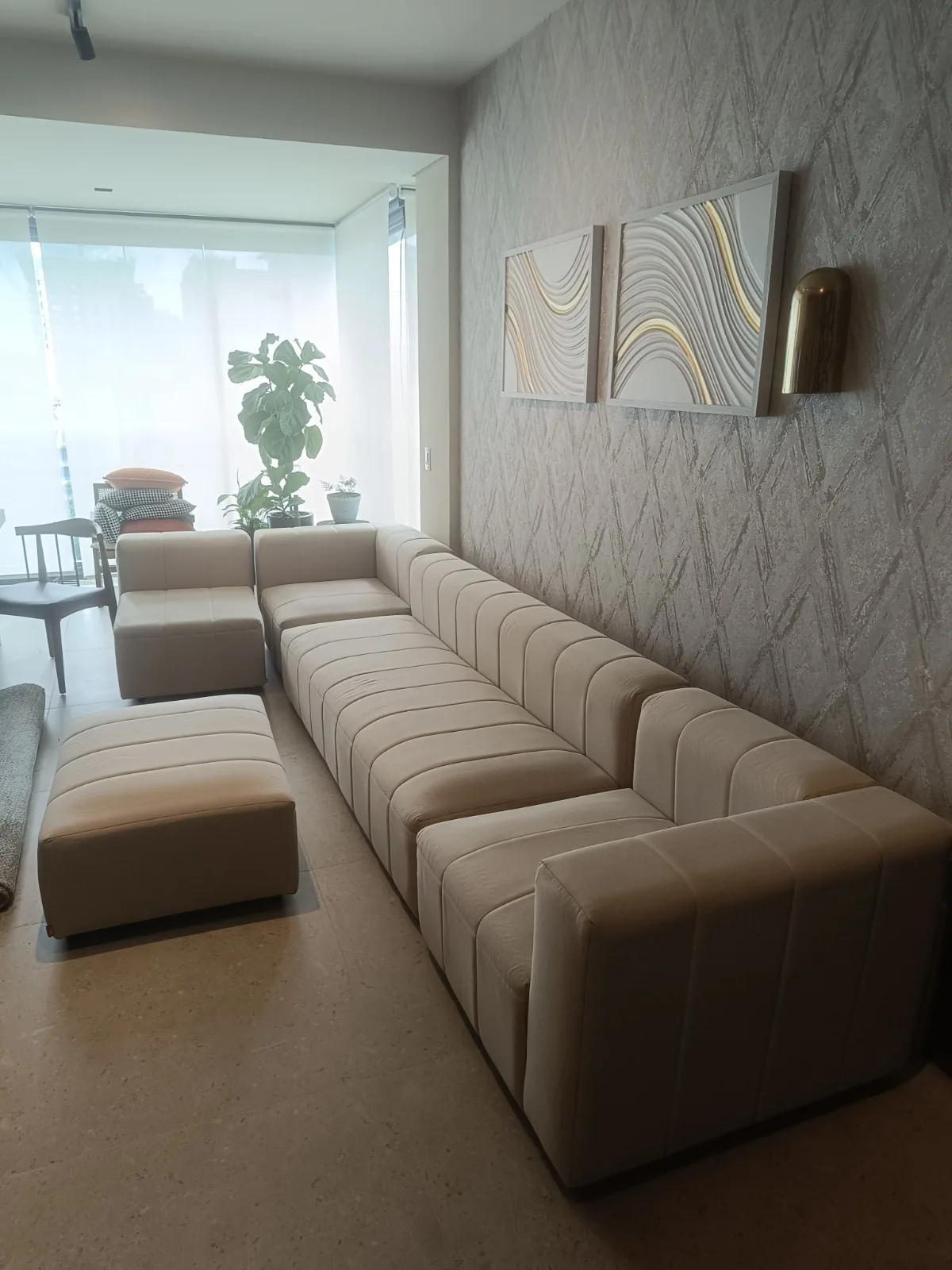 Sofá modular bege em sala alongada