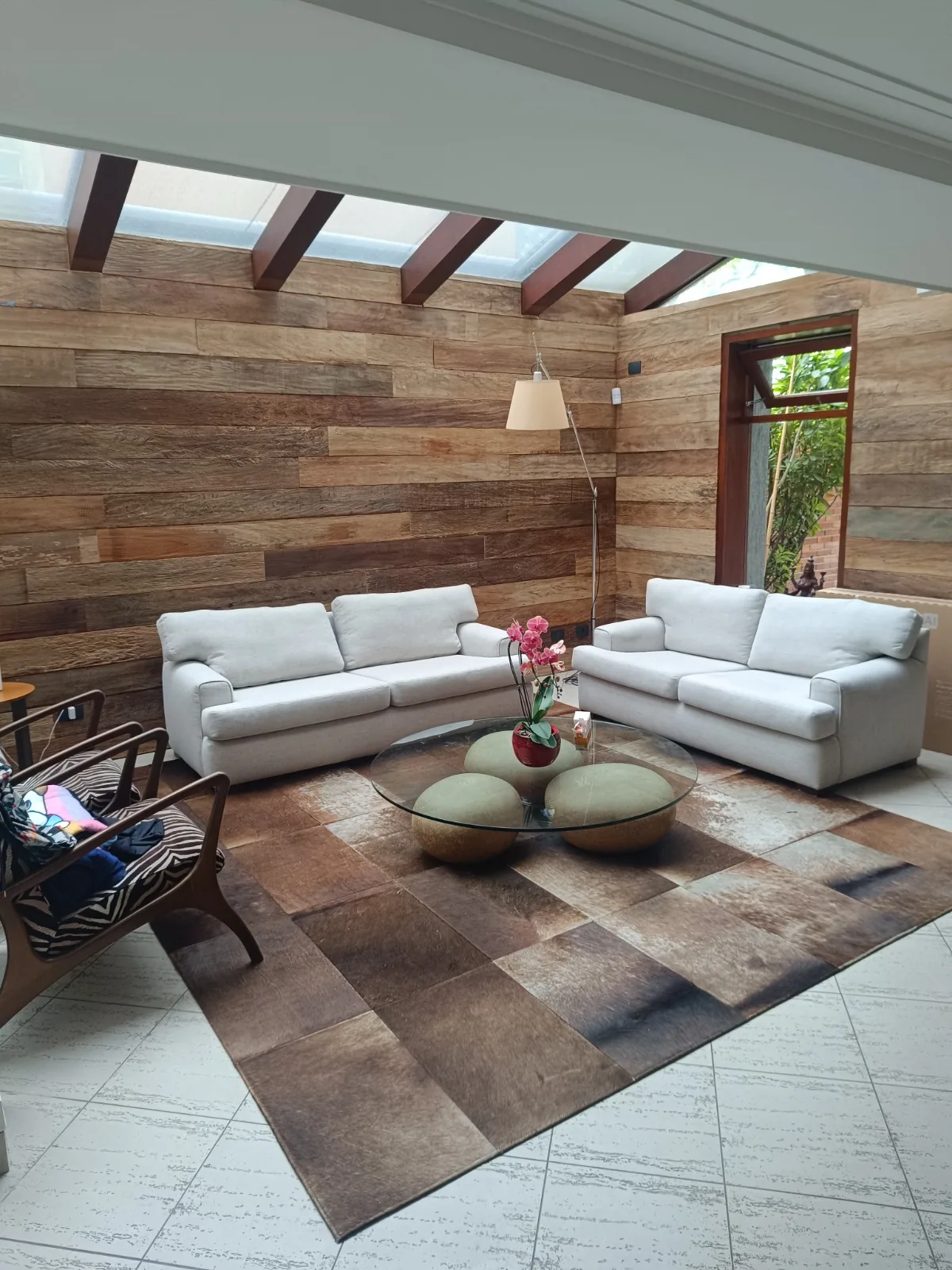 Sala com teto de madeira e sofás brancos higienizados