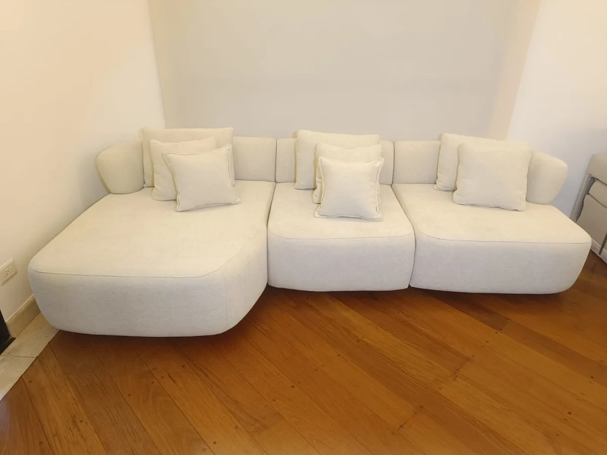 Sofá curvo de bouclé branco higienizado sobre piso de madeira